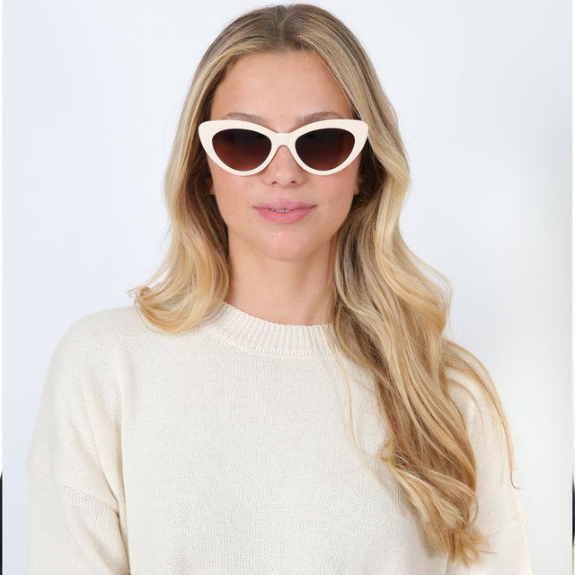 Blonde model with loose curls wearing Pamela Sunglasses Cream with Brown Flat Gradient