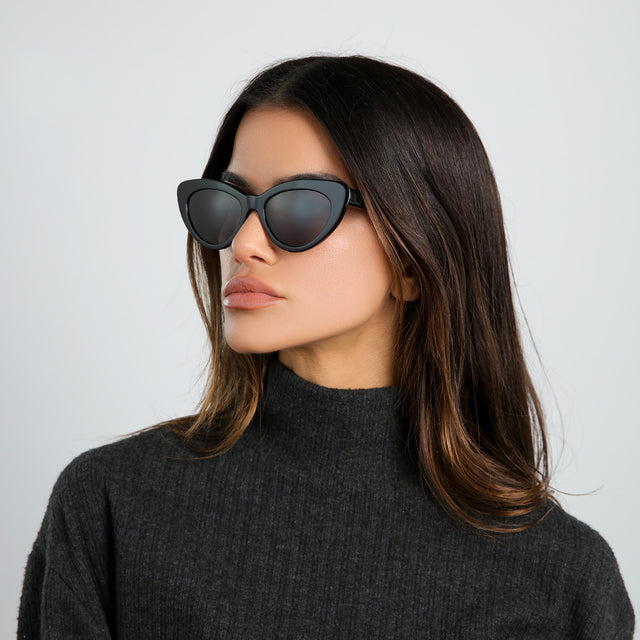 Brunette model in a heather grey cashmere turtleneck looking right wearing Pamela Sunglasses Black with Grey Flat