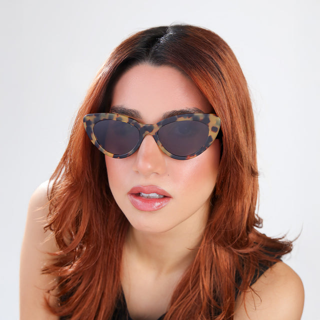 Woman with red hair in a black blouse wearing Pamela Sunglasses Tortoise with Grey Flat