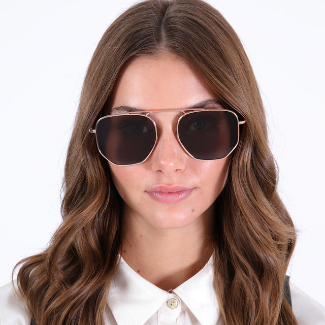 Brunette model wearing Patmos 58 Sunglasses Rose Gold with Brown Flat
