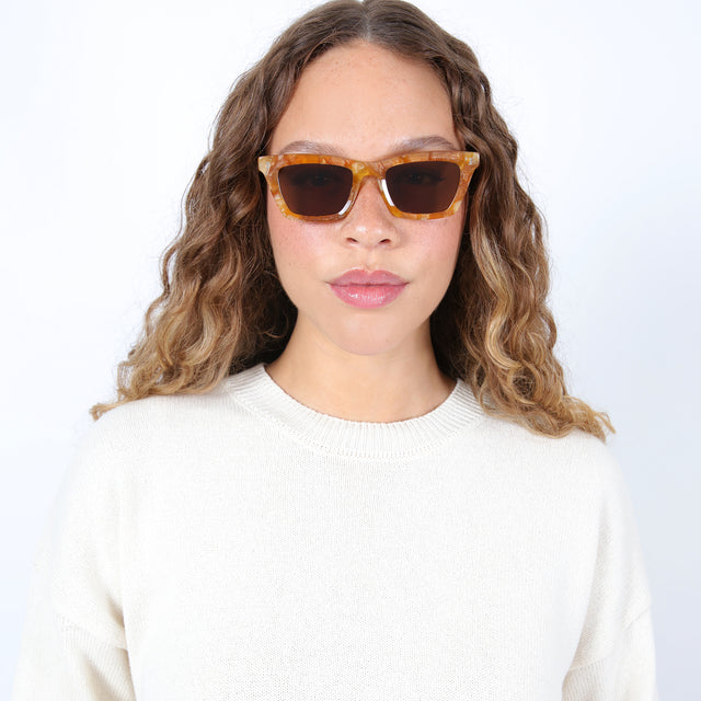 Brunette model with ombré hair wearing Portugal Sunglasses Topaz with Brown Flat