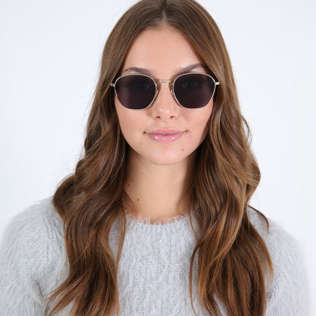 Brunette model with loose curls wearing Prince Sunglasses Rose Gold with Grey Flat