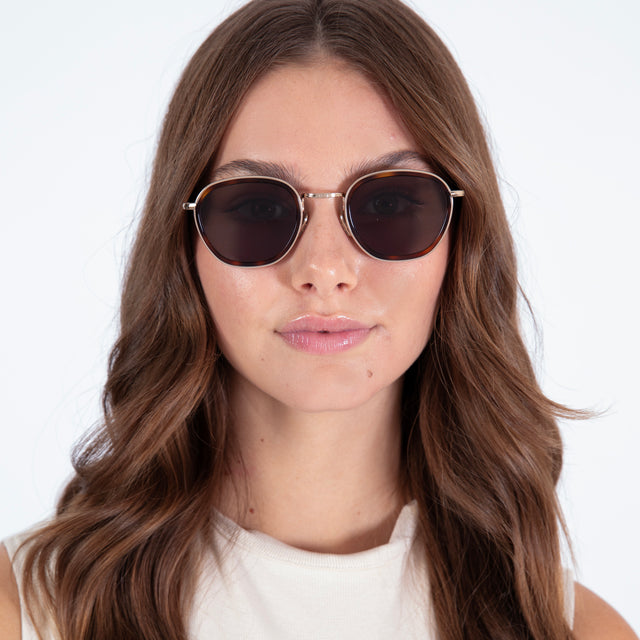 Brunette model with curled hair wearing Prince Tate Sunglasses Havana/Gold with Grey Flat
