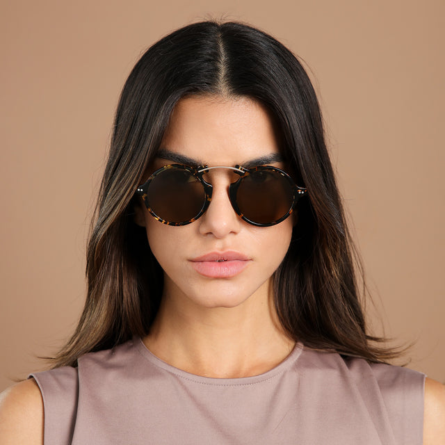 Brunette model in a clay blouse wearing Roma II Sunglasses Flame/Gold with Brown Flat