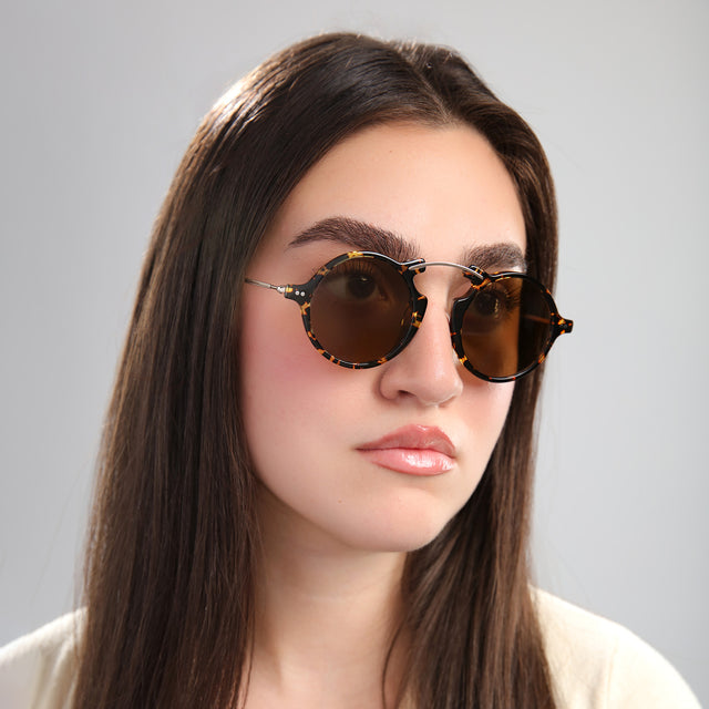 Another angle of brunette model in front of a grey wall wearing Roma II Sunglasses Flame/Gold with Brown Flat