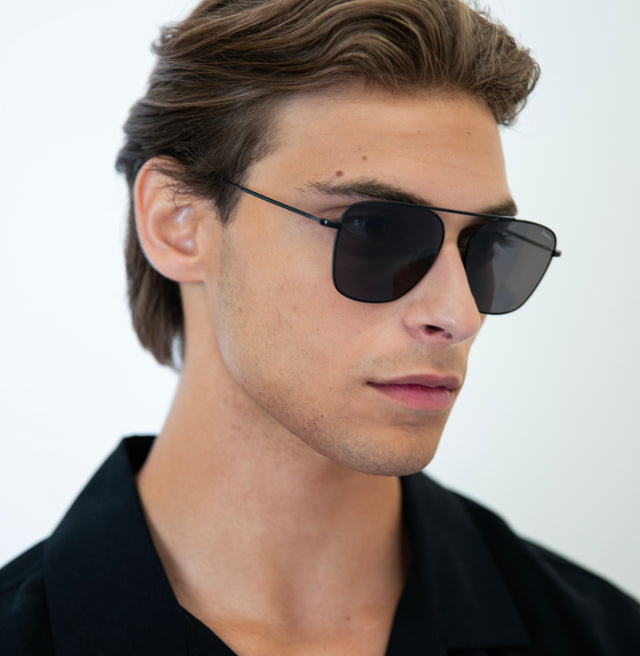 Model with wavy hair pushed back wearing Samos Sunglasses Black with Grey Flat