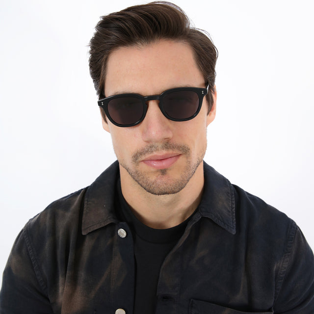Model with brown hair combed sideways wearing Slope Sunglasses Black with Grey