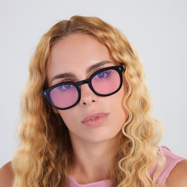 Woman with blonde, wavy hair wearing Slope Sunglasses Black with Dusty Pink Flat See Through