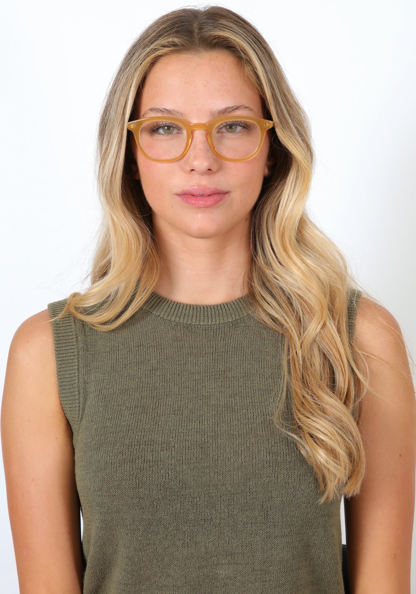 Blonde model with loose curls in a sage, knit high neck blouse wearing Slope Optical in Blond