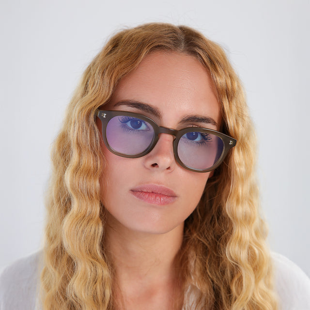 Woman with blonde, wavy hair wearing Slope Sunglasses Olive with Pale Blue Flat See Through