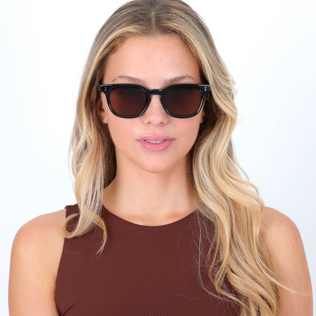 Blonde model with curled hair wearing Veneto Sunglasses Black with Brown Flat