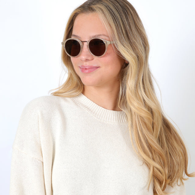 Blonde model with beach waves wearing Village Sunglasses Bone/Rose Gold with Brown