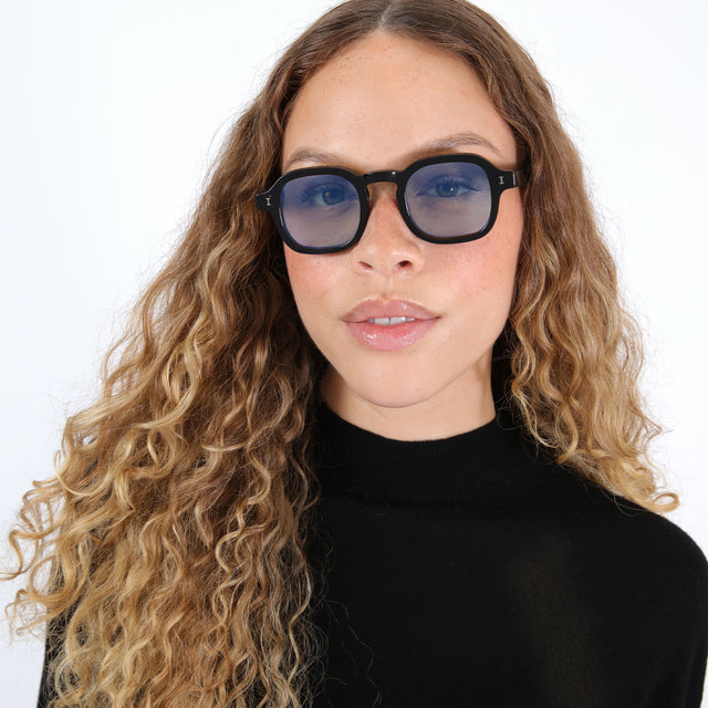 Brunette model with ombré, wavy hair wearing Washington Sunglasses Black with Blue Flat Gradient See Through