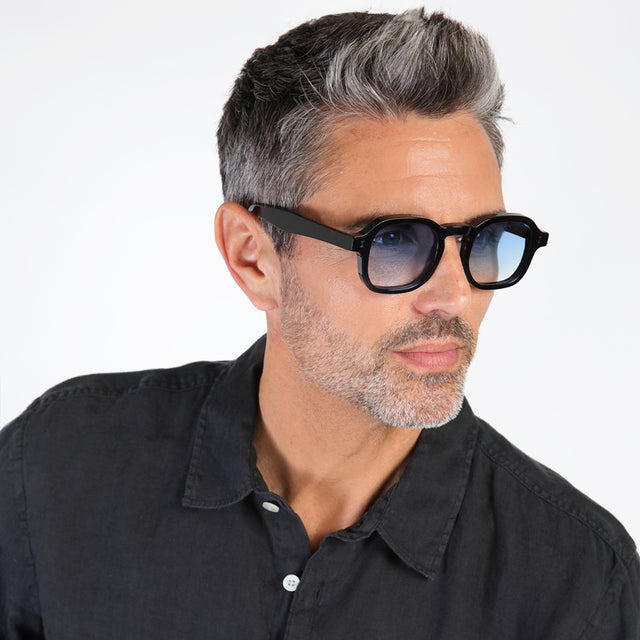 Model with salt and pepper hair and beard looking left wearing Washington Sunglasses Black with Blue Flat Gradient See Through