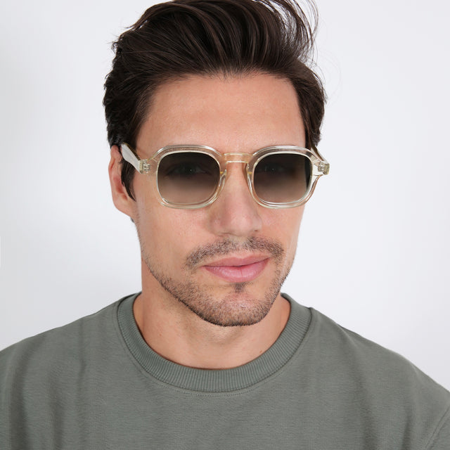 Model with brown hair combed sideways wearing Washington Sunglasses Champagne with Olive Flat Gradient