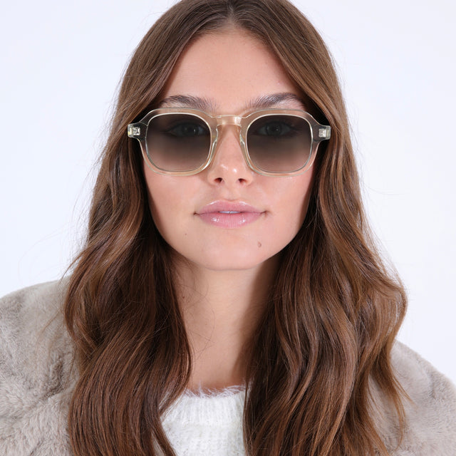 Brunette model with curled hair in a white fuzzy coat wearing Washington Sunglasses Champagne with Olive Flat Gradient