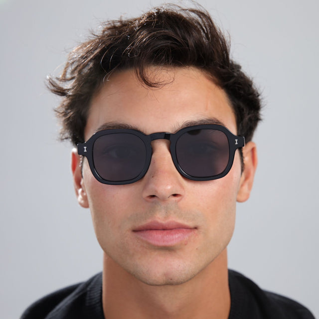 Man with brown hair in a black shirt wearing Washington Sunglasses Black with Grey Flat