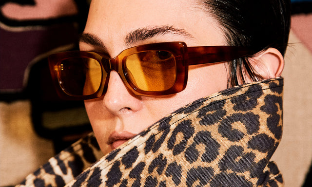Model peaking over leopard print collar wearing nk x illesteva Wilson Sunglasses Red Havana with Honey Flat See Through