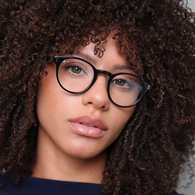 Brunette model with natural tight curls wearing Wyoming Optical Black Optical
