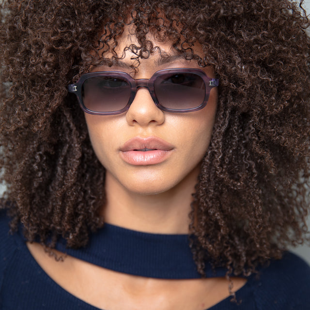 Brunette model with curly hair wearing Berlin Sunglasses Purple Aurora with Grey Gradient