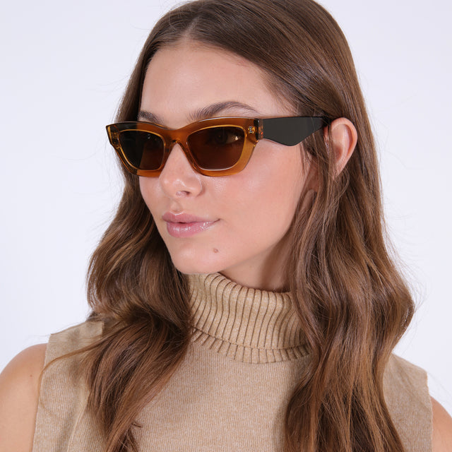 Brunette model looking right wearing nk x illesteva Donna Sunglasses Cider/Black with Brown