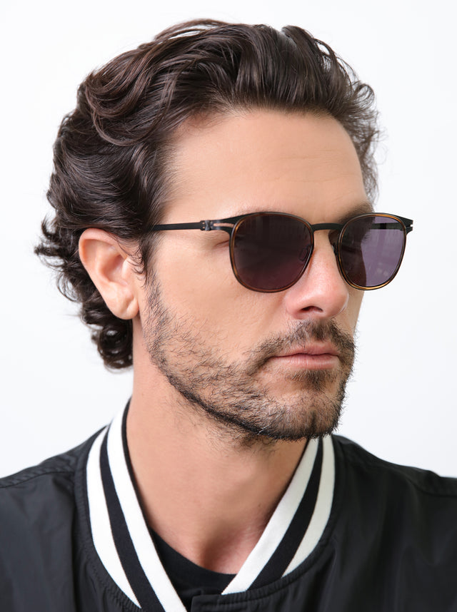 Model with wavy hair wearing Astor Titanium Sunglasses Scotch/Matte Black with Grey
