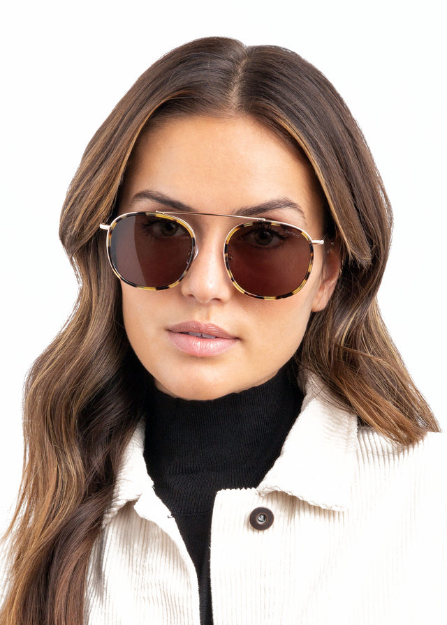 Brunette model with wavy hair wearing Mykonos Ace Sunglasses Tortoise/Gold with Grey Flat