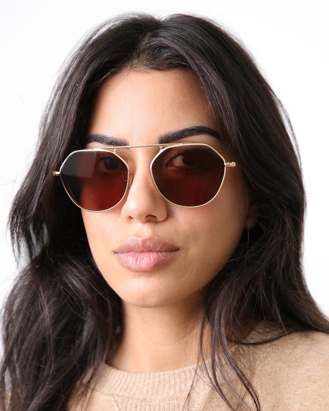 Model with dark brown, wavy hair wearing Nicosia 57 Sunglasses Rose Gold with Brown Flat