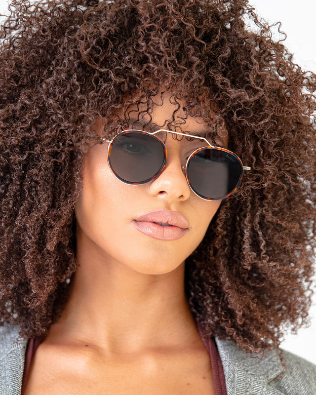 Brunette model with afro-curly hair wearing Wynwood Ace Sunglasses Havana/Gold with Grey Flat Lenses