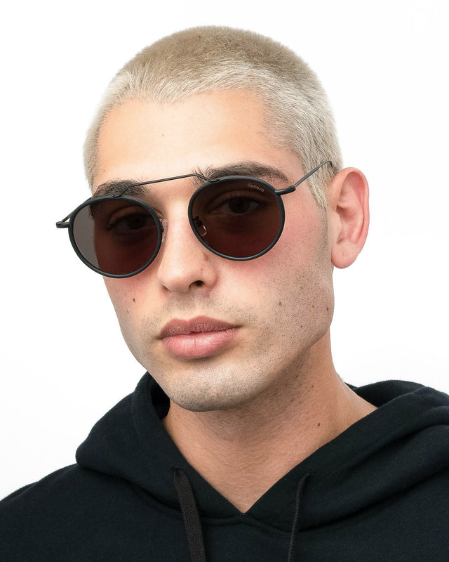 Model with blonde buzzcut wearing Wynwood Ace Sunglasses Matte Black with Grey Flat Lenses