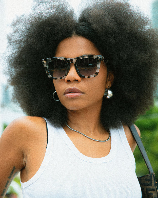Model with afro-textured hair in a park wearing Charleston Sunglasses White Tortoise with Grey Flat Gradient