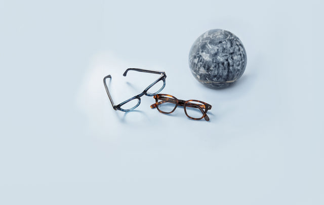 Pacific Optical shown in two colors near a round, gray marble ball