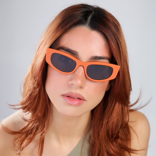 Another angle of woma  with red hair in an olive blouse wearing Alexa Sunglasses Aperol with Grey Flat