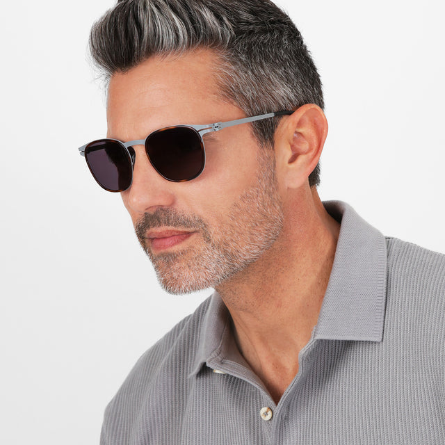 Isometric angle of a model in a knit polo wearing Astor Titanium Sunglasses Havana/Matte Gunmetal with Grey
