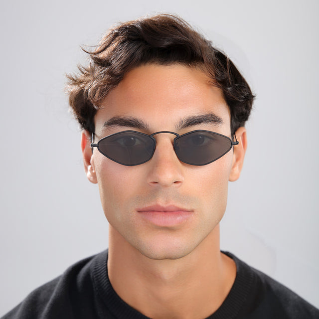 Man in a black tee wearing Astoria Sunglasses Matte Black with Grey Flat