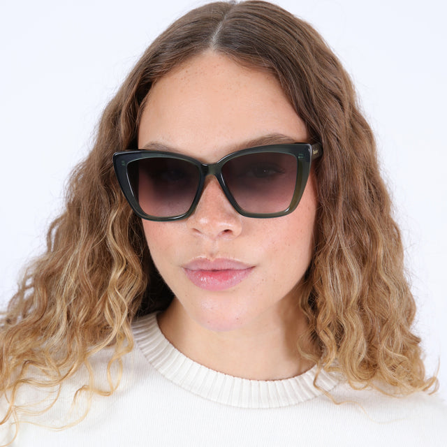 Brunette model with ombré, wavy hair wearing Barcelona Sunglasses Pine with Grey Flat Gradient