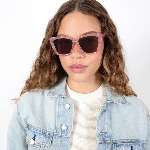 Brunette model with ombré, wavy hair wearing Barcelona Sunglasses Rose Quartz with Brown Flat