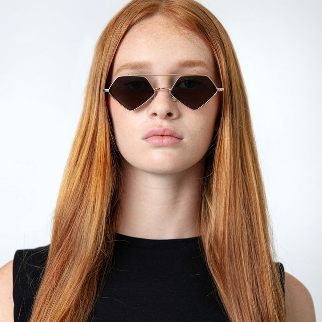 Model with long red hair wearing Bayley Sunglasses Gold with Grey Flat