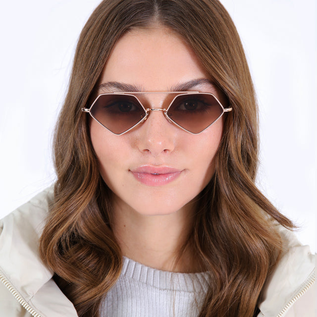 Brunette model in a white puffer jacket wearing Bayley Sunglasses Rose Gold with Brown Flat Gradient