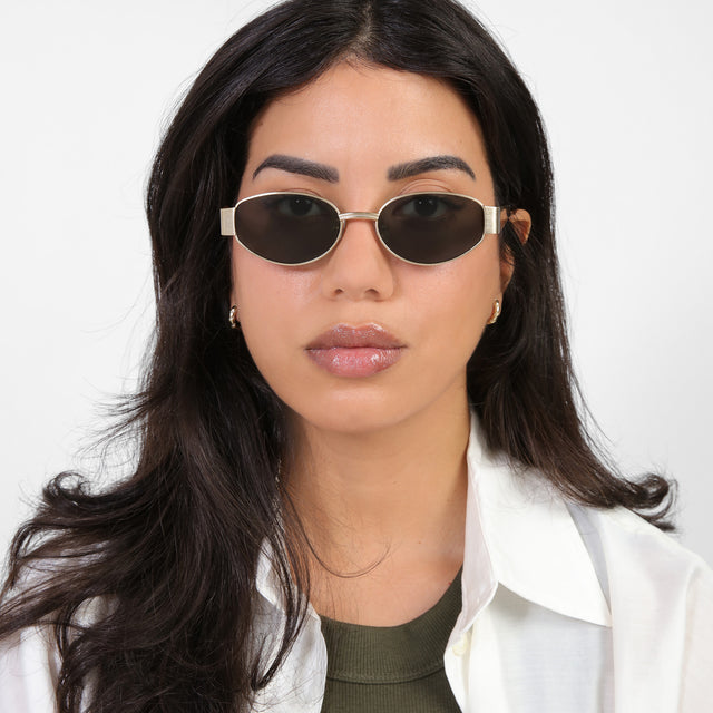 Brunette model in a cream blouse wearing Bellagio Sunglasses Brushed Gold with Grey