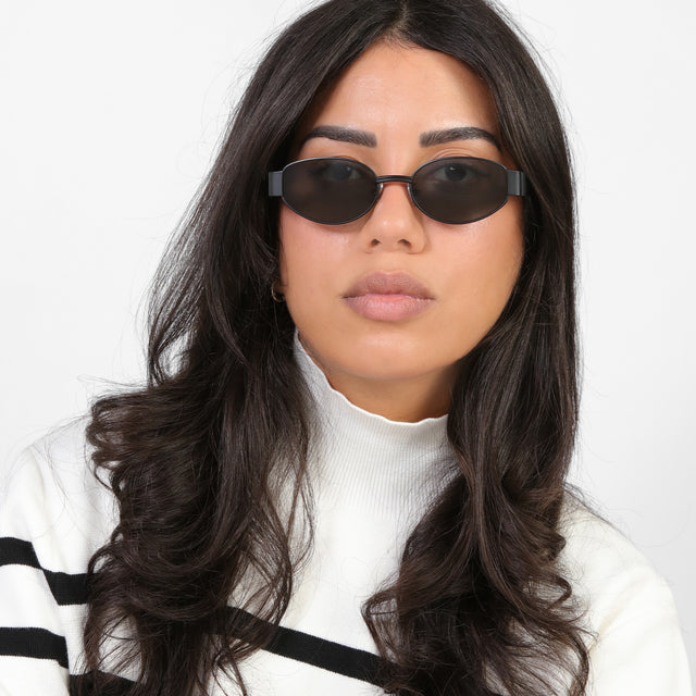 Close up of model in a black and white striped turtleneck wearing Bellagio Sunglasses Matte Black with Grey