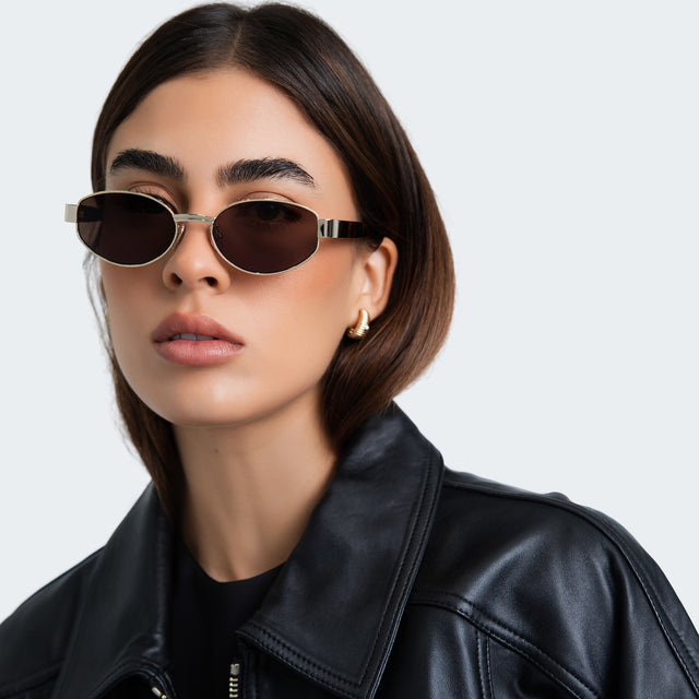 Woman in a black blouse wearing Bellagio A Sunglasses Gold/Havana with Grey