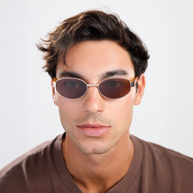 Man with brown hair in a brown shirt wearing Bellagio A Sunglasses Rose Gold/Honey Gold with Brown