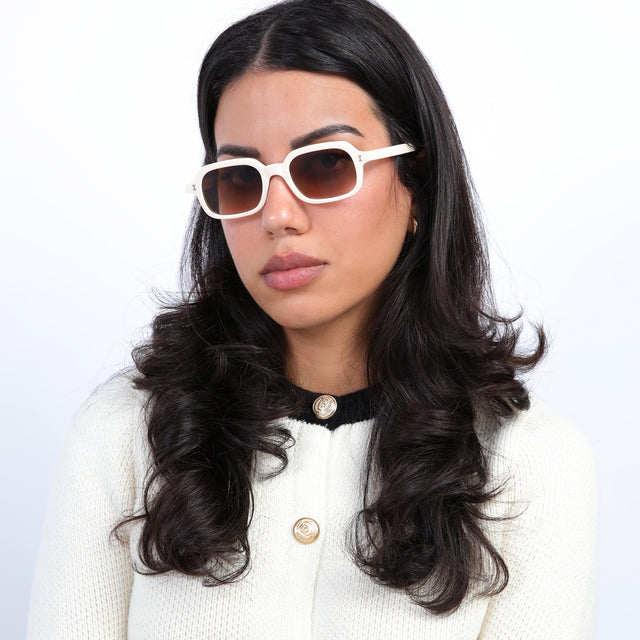 Brunette model with loose curls wearing Berlin Sunglasses Cream with Brown Gradient