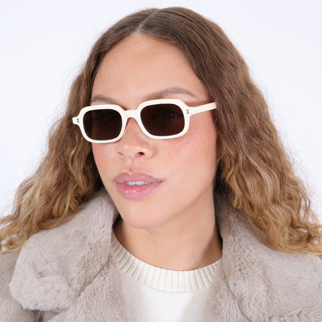 Brunette model with ombré, wavy hair wearing Berlin Sunglasses Cream with Brown