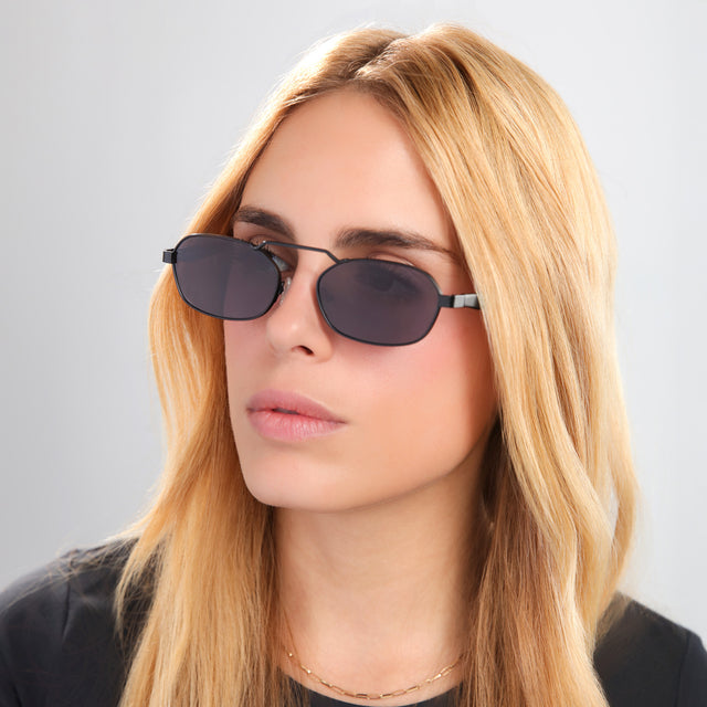 Another angle of blond woman in a black tee wearing Bimini Sunglasses Matte Black with Grey Flat