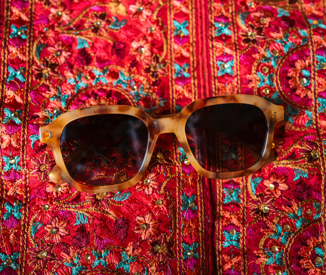 Bogota in Amber with Brown Gradient lenses on a colorful cloth