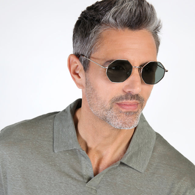Model with salt and pepper hair and beard looking left wearing Broome Sunglasses Gold with Olive Flat