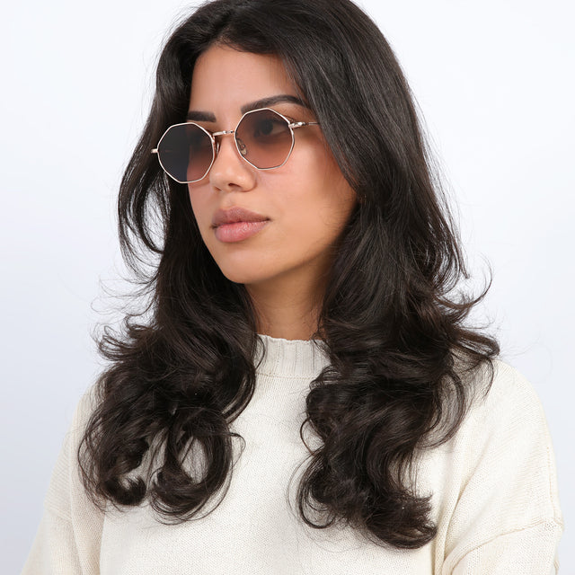 Brunette model with curls looking right wearing Broome Sunglasses Rose Gold with Brown Flat Gradient