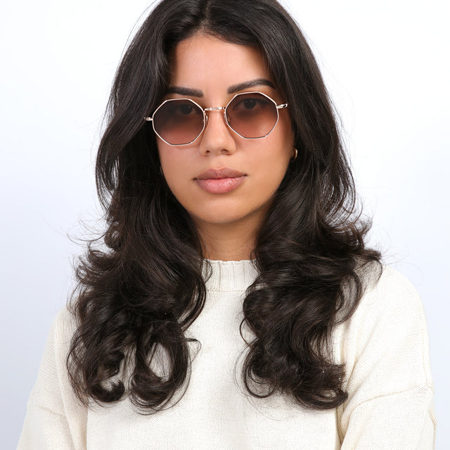 Brunette model with curls wearing Broome Sunglasses Rose Gold with Brown Flat Gradient